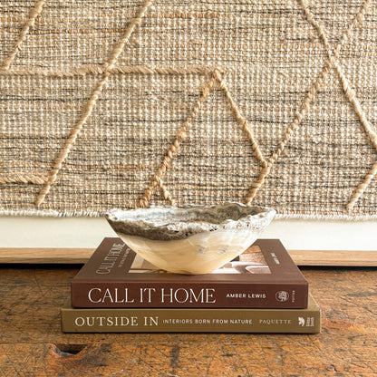 Decorative natural stone bowl on top of two books with a textured wall in the background