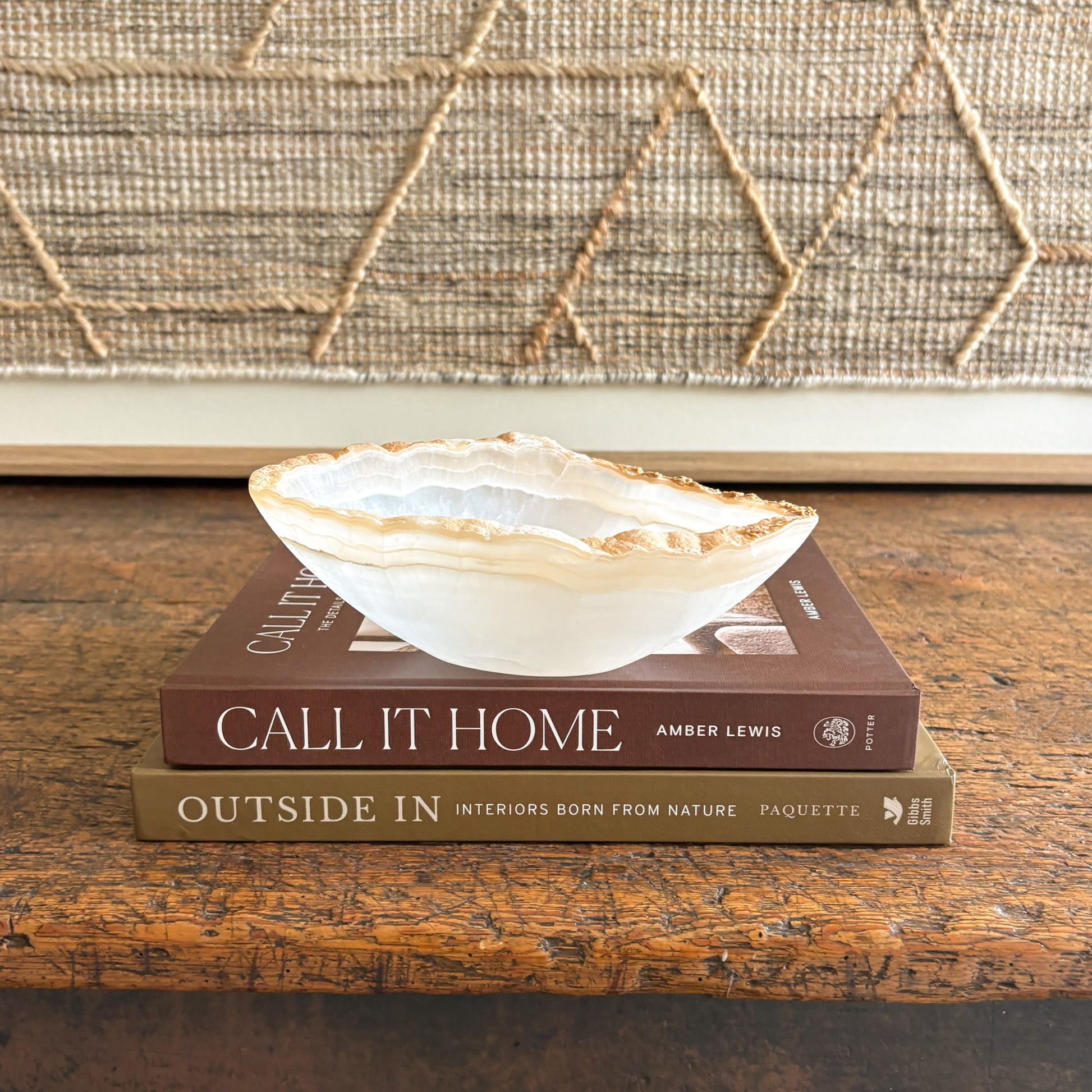 Decorative  onyx bowl on top of two books with a textured wall in the background
