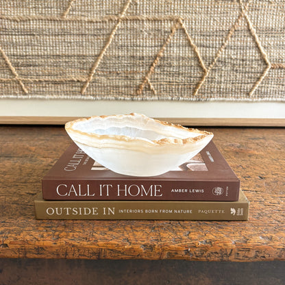 Decorative  onyx bowl on top of two books with a textured wall in the background