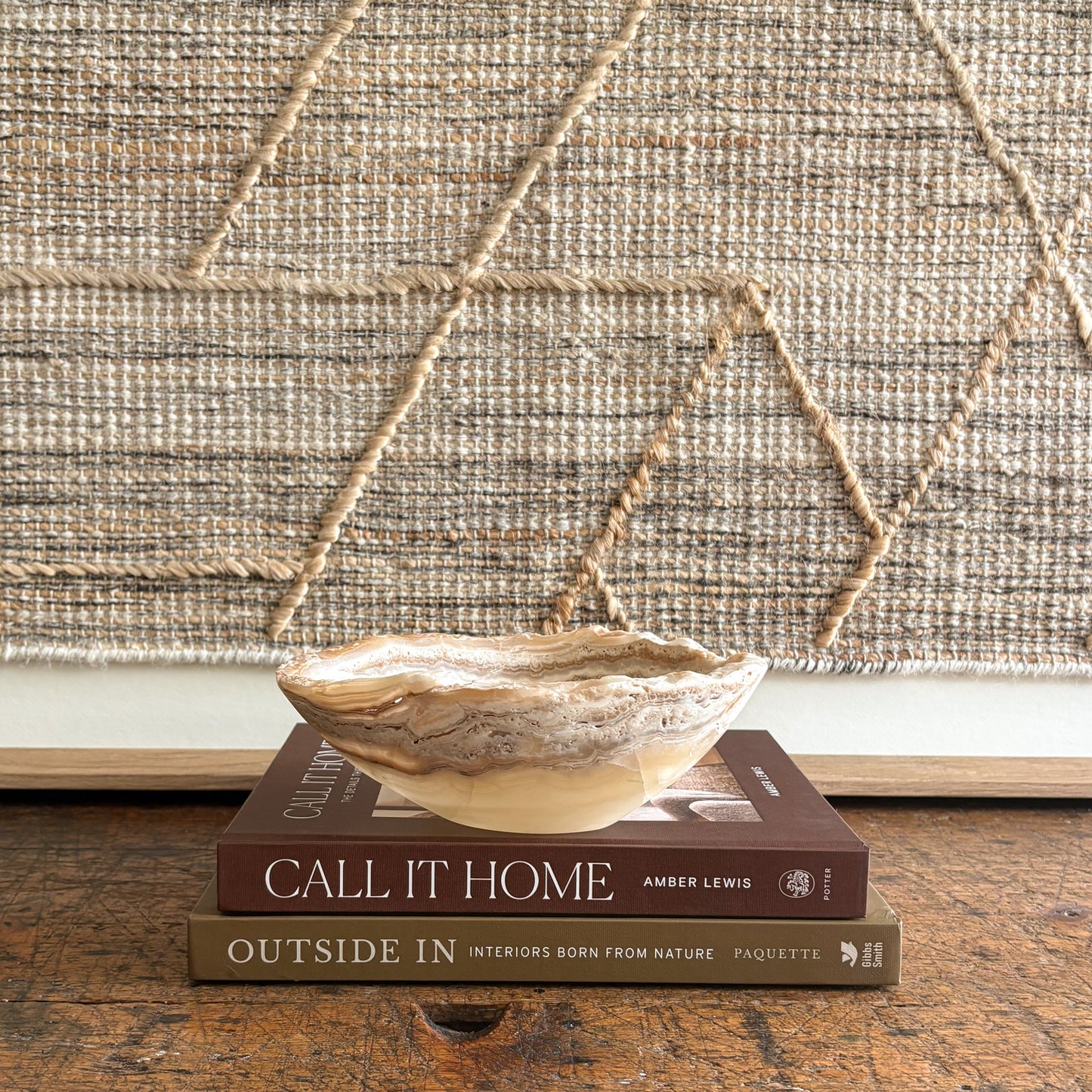 decorative onyx bowl on books with a textured wall in the background