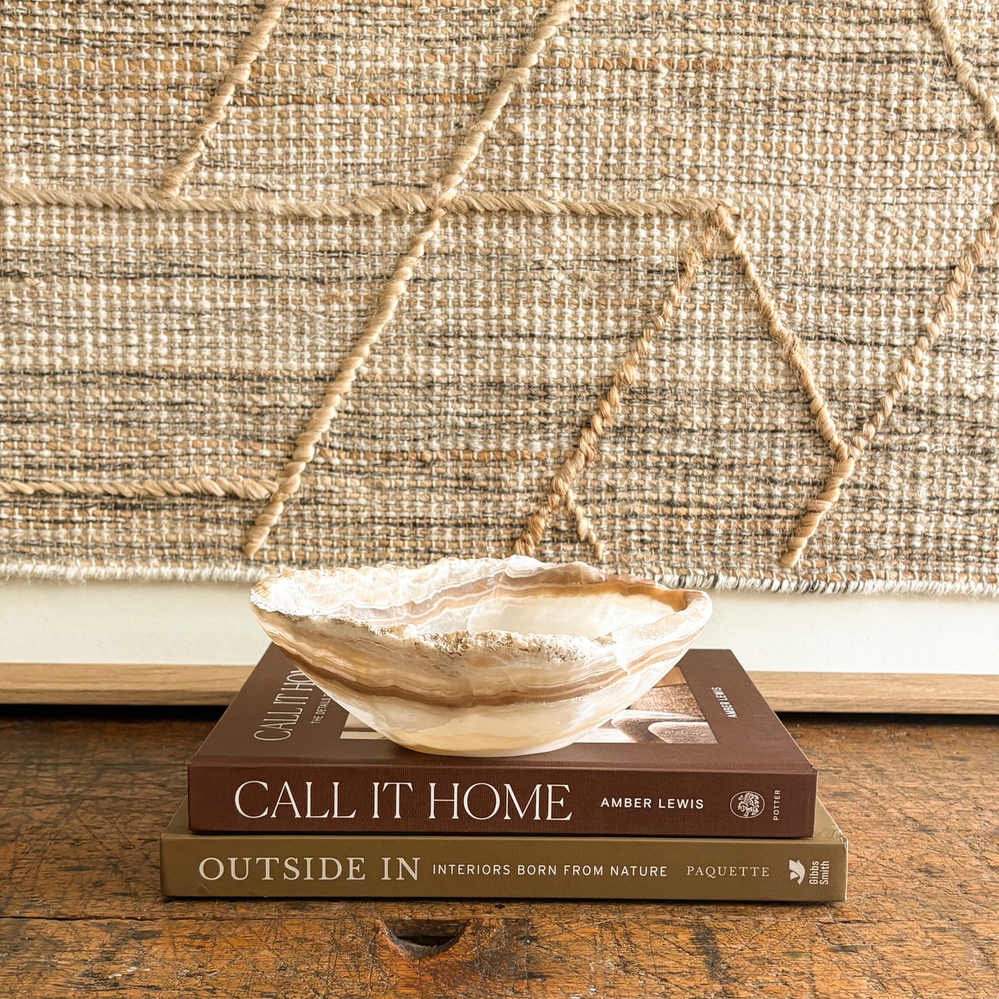 Decorative onyx bowl on top of two books with a textured wall in the background