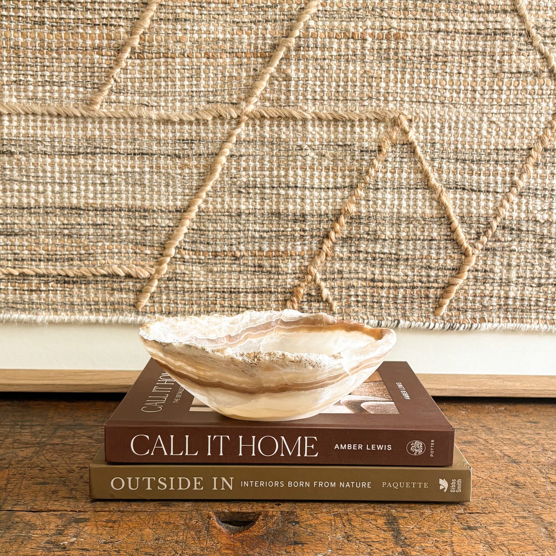 Decorative onyx bowl on top of two books with a textured wall in the background