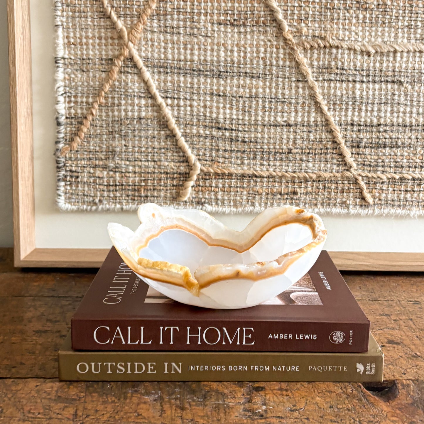 Decorative onyx bowl on top of books with a textured wall in the background