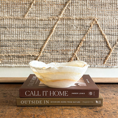 Decorative onyx bowl on a stack of books with a textured wall in the background