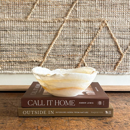Decorative onyx bowl on a stack of books with a textured wall in the background