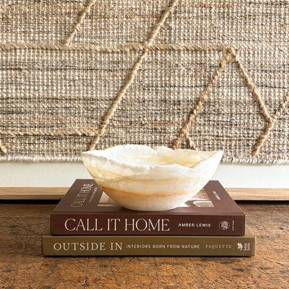 Decorative stone bowl on books with a textured wall in the background