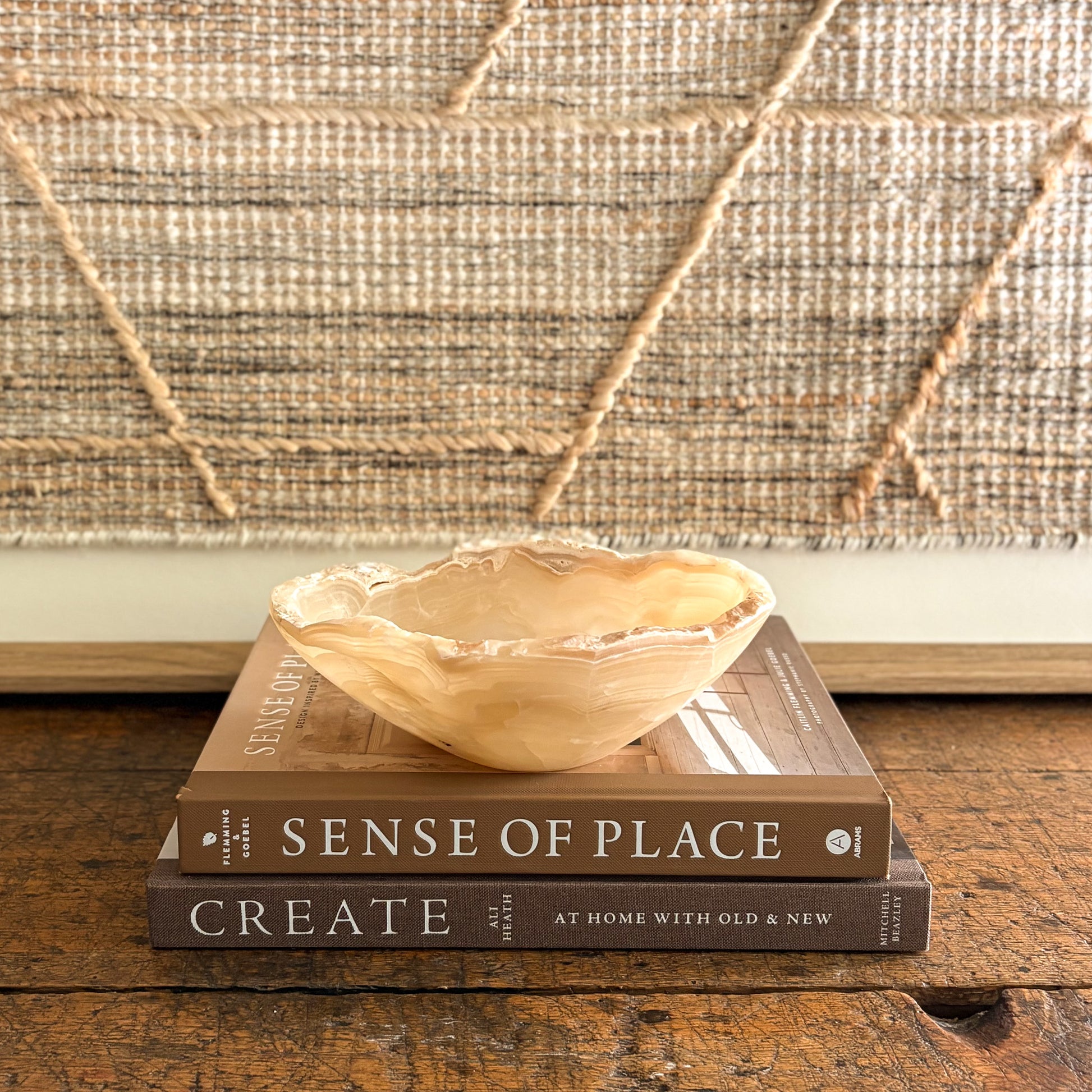 Decorative amber onyx bowl on books against a woven textured wall
