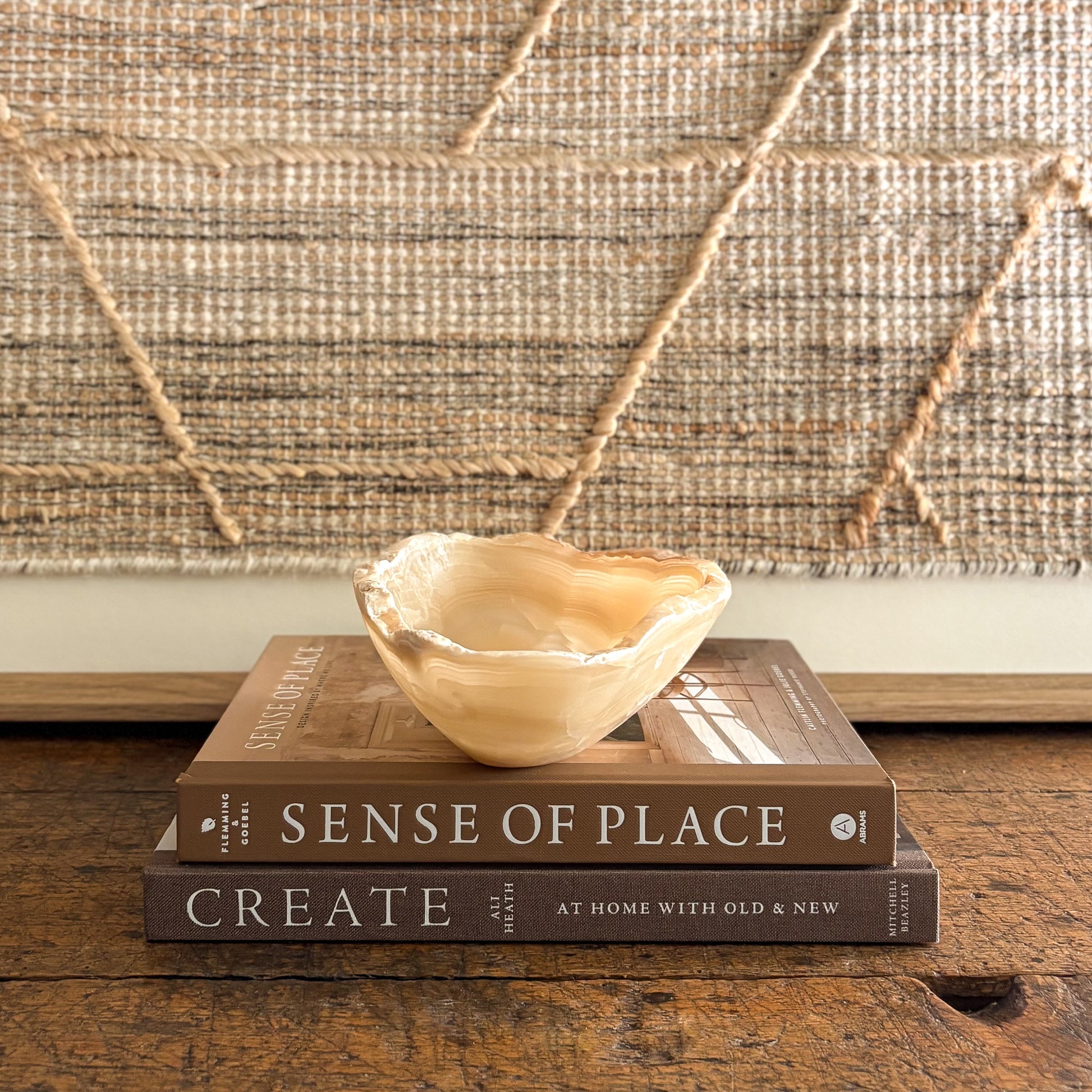 Polished amber onyx bowl styled as home décor on stacked design books