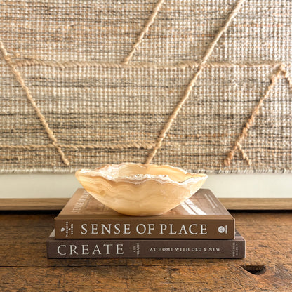 Hand-carved amber onyx bowl for décor or jewelry storage, styled on coffee table books