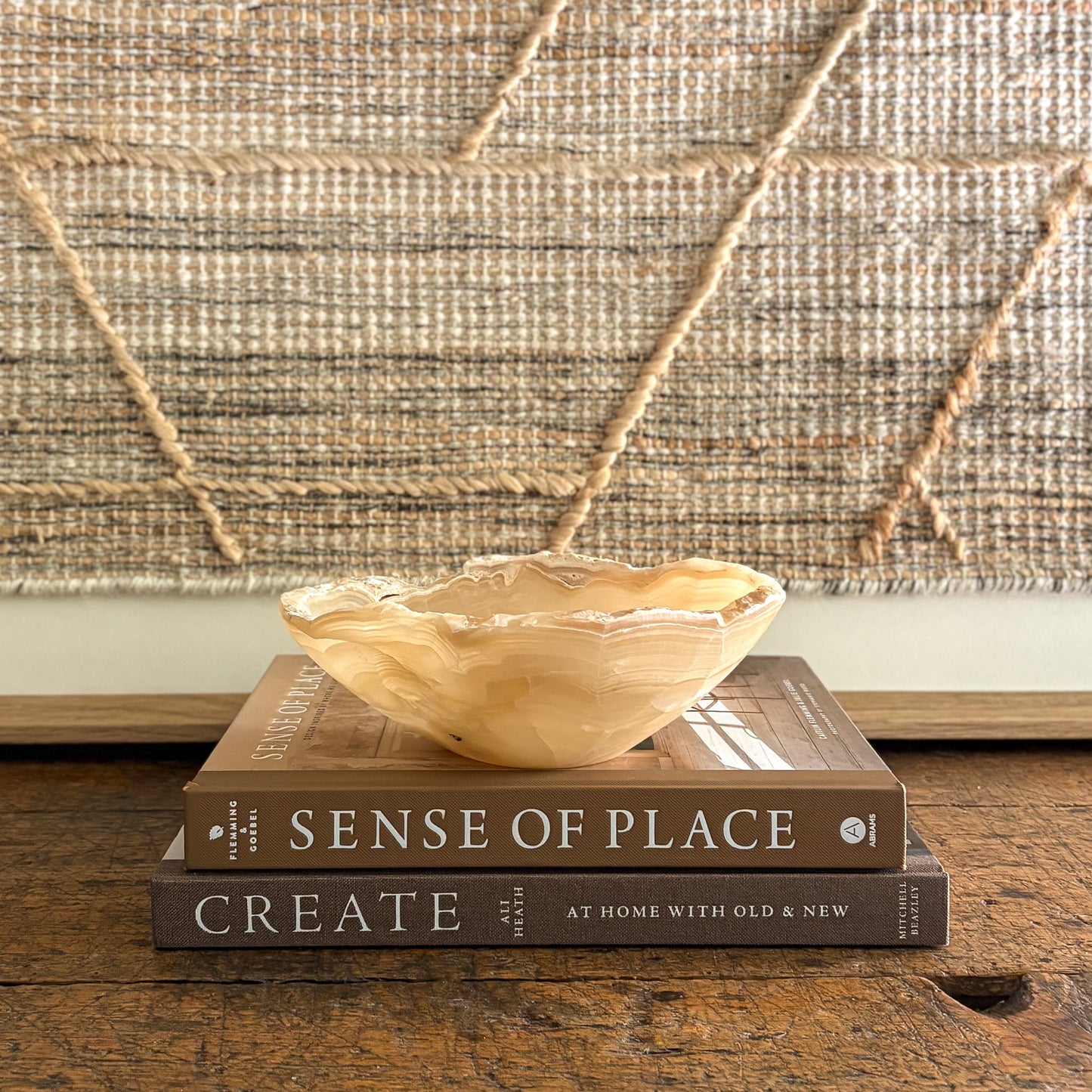 Hand-carved amber onyx bowl displayed on stacked books in a neutral home setting