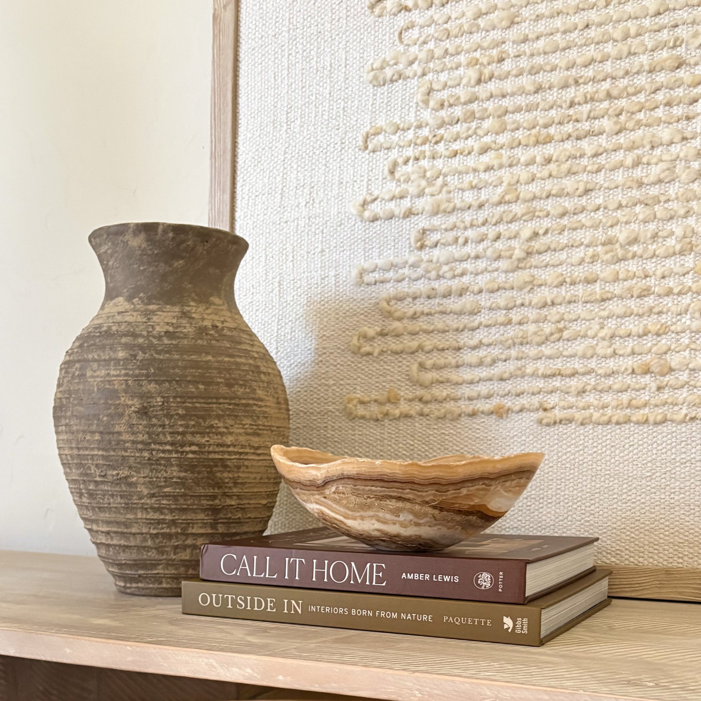 Small hand carved amber onyx bowl with soft natural veining displayed on stacked design books