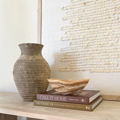 Small amber onyx bowl styled on wooden surface with neutral wall art