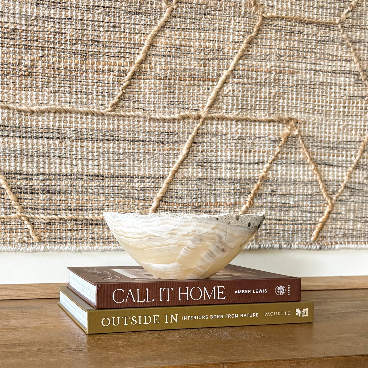 Small hand-carved grey onyx bowl with natural banded stone pattern displayed on stacked books in modern home decor setting