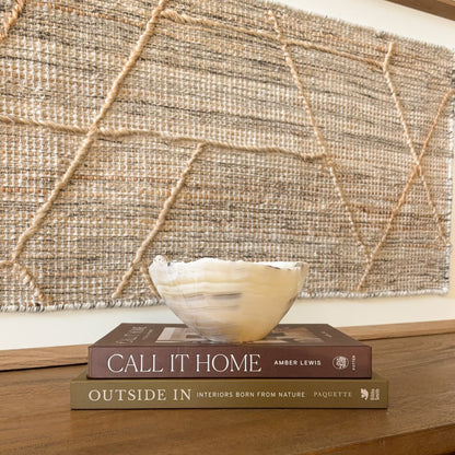 Small polished amber onyx bowl with organic wavy edge and natural striped veining, minimalist stone decor piece