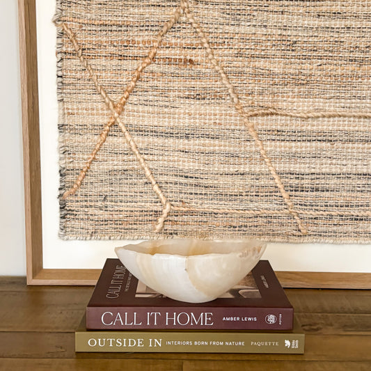 Small hand carved amber onyx bowl with soft natural veining displayed on stacked design books