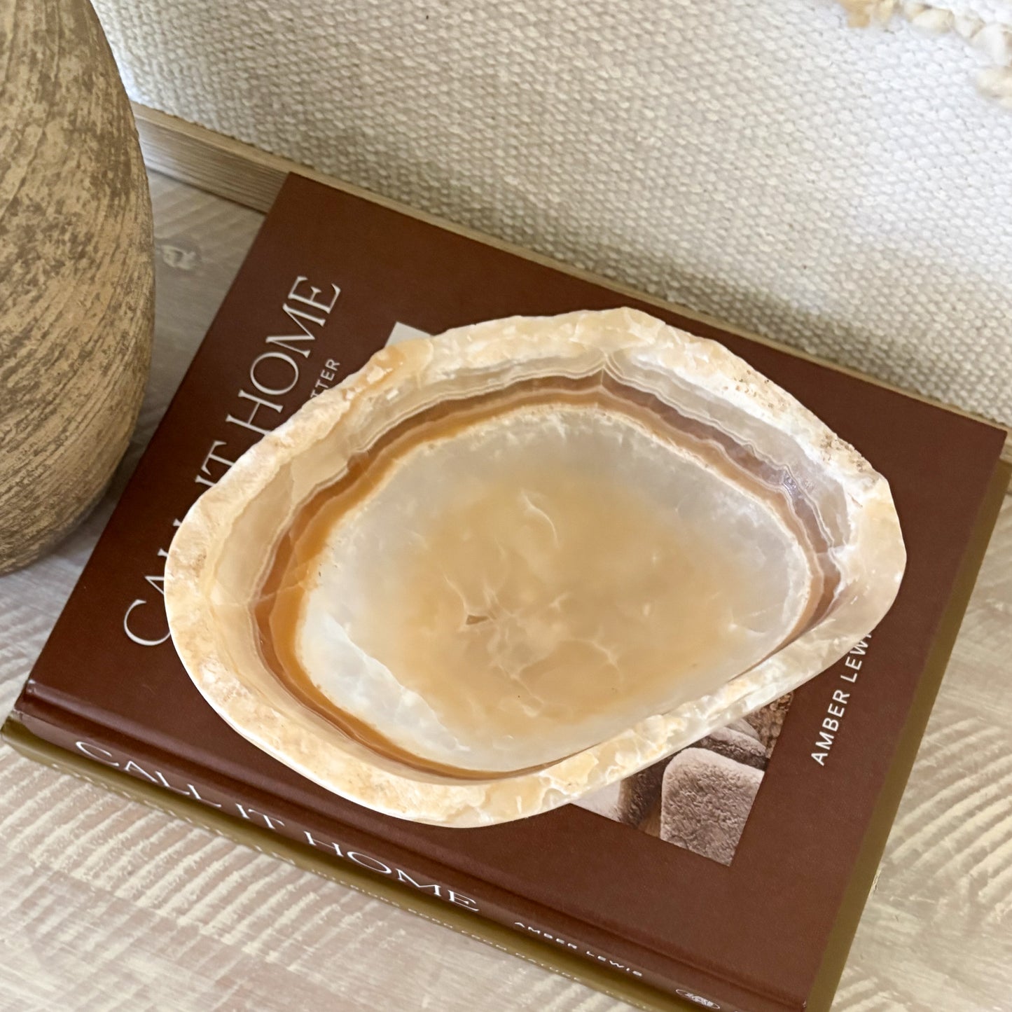 Small hand carved amber onyx bowl with soft natural veining displayed on stacked design books