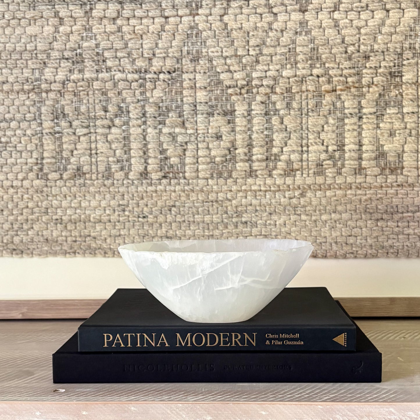 White onyx stone bowl on a stack of books with a textured wall background