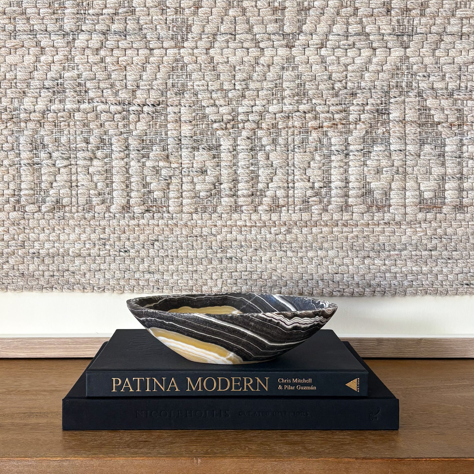 Small zebra onyx bowl styled on stacked design books in neutral modern interior