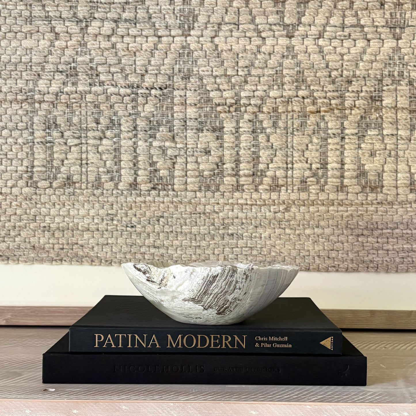 Decorative stone bowl on a book with textured wall in the background