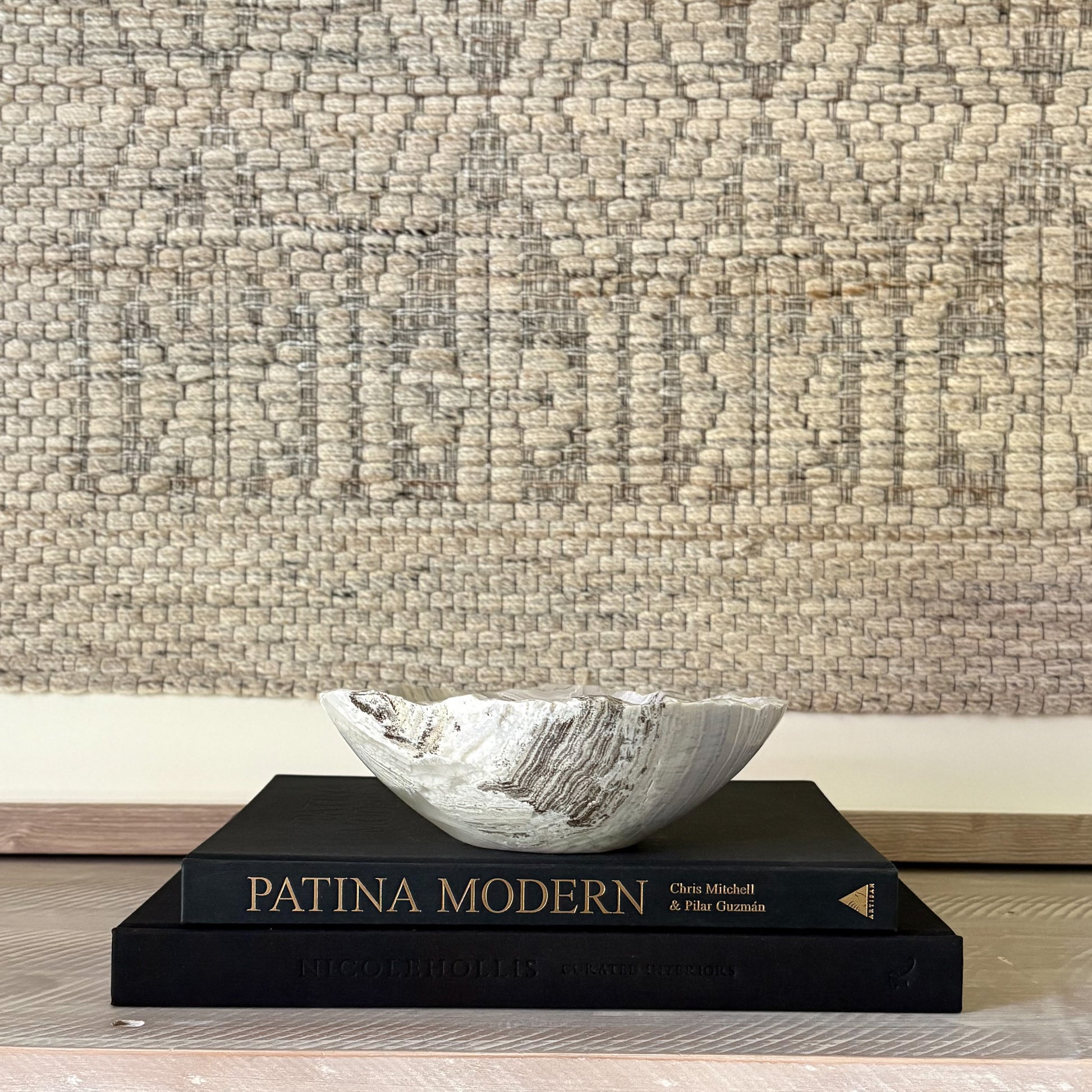 Decorative stone bowl on a book with textured wall in the background