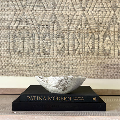 Decorative stone bowl on a book with textured wall in the background