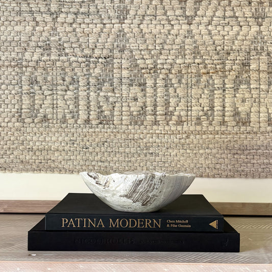 Decorative stone bowl on a book with textured wall in the background