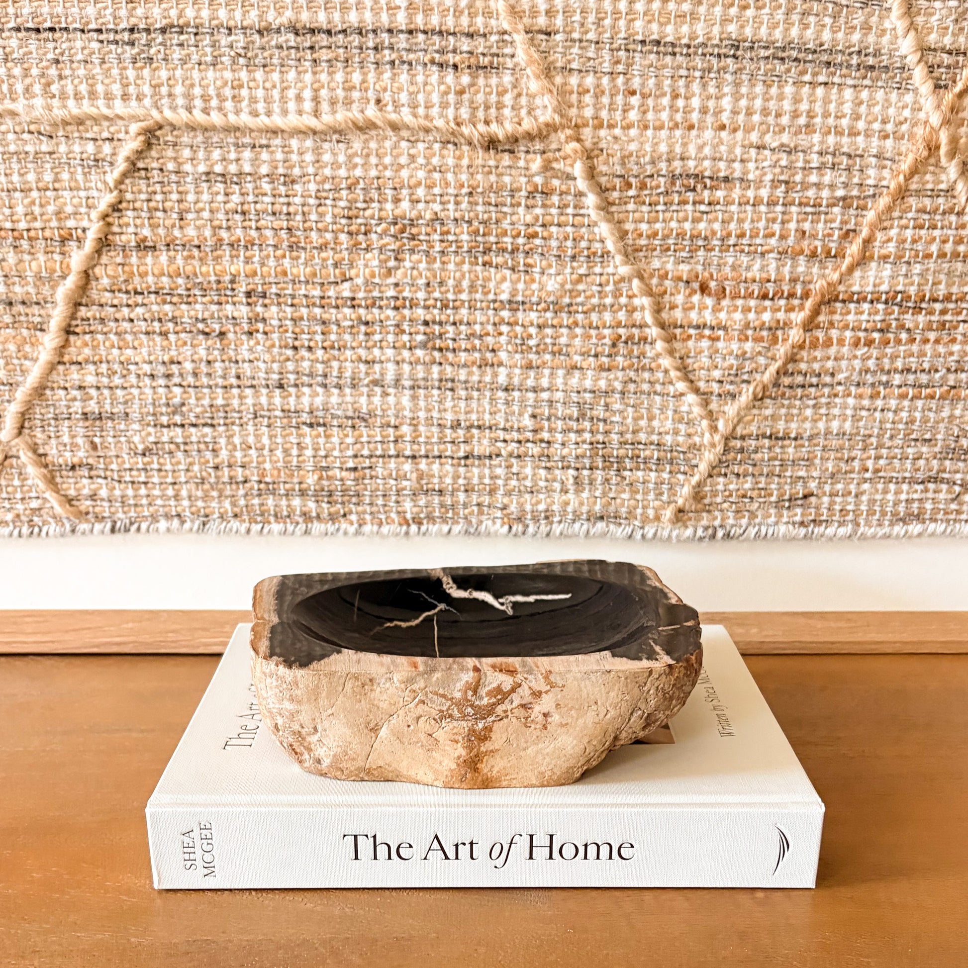 Small petrified wood bowl styled on console table with neutral decor