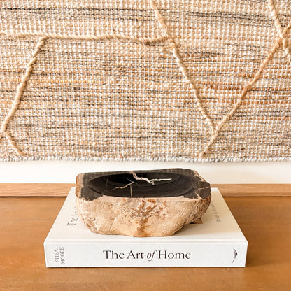 Small petrified wood bowl styled on console table with neutral decor