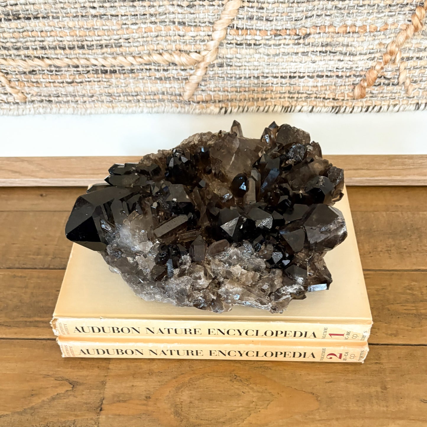 Smoky quartz crystal cluster styled on stacked books for earthy modern home decor
