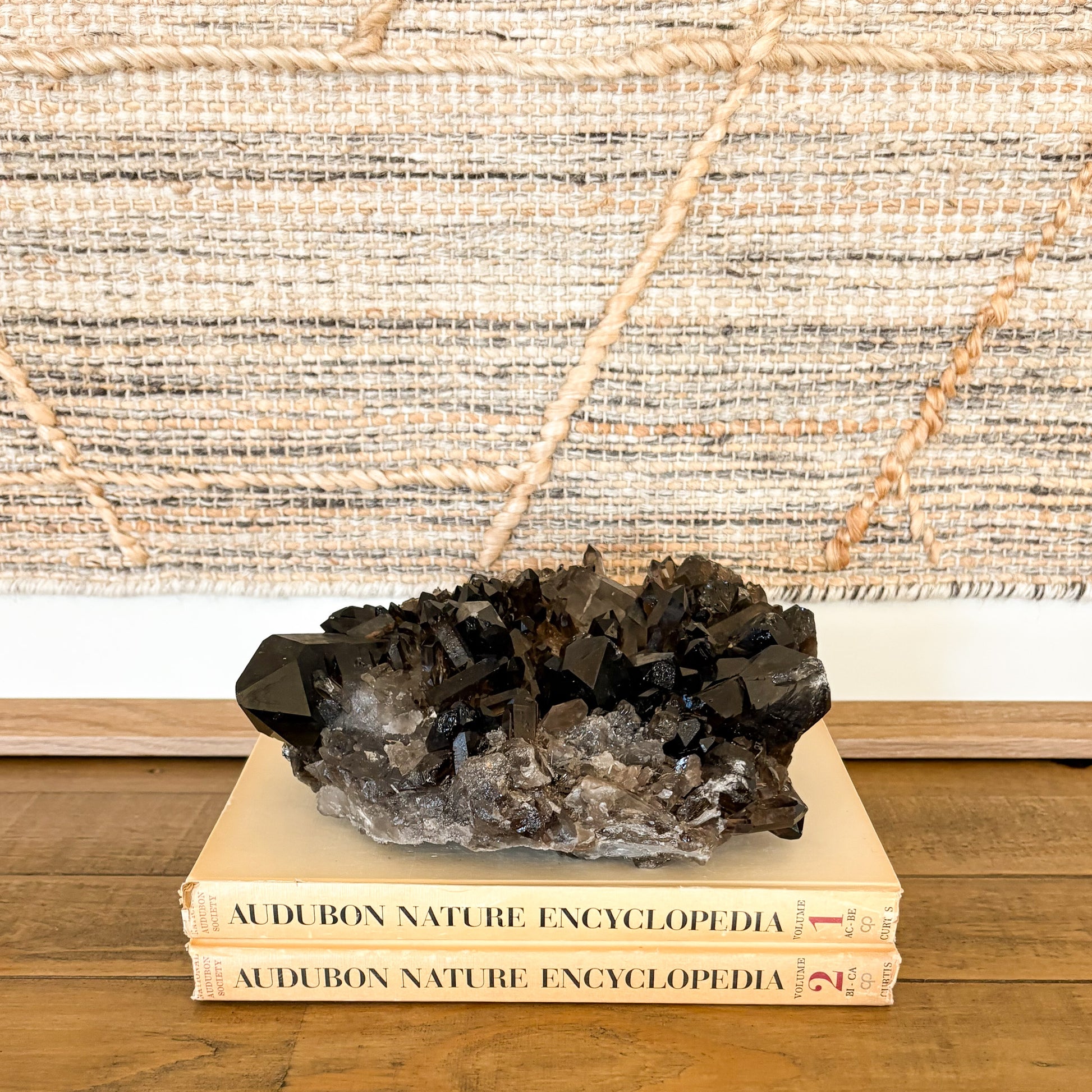 Raw smoky quartz crystal cluster with deep brown crystals styled on books