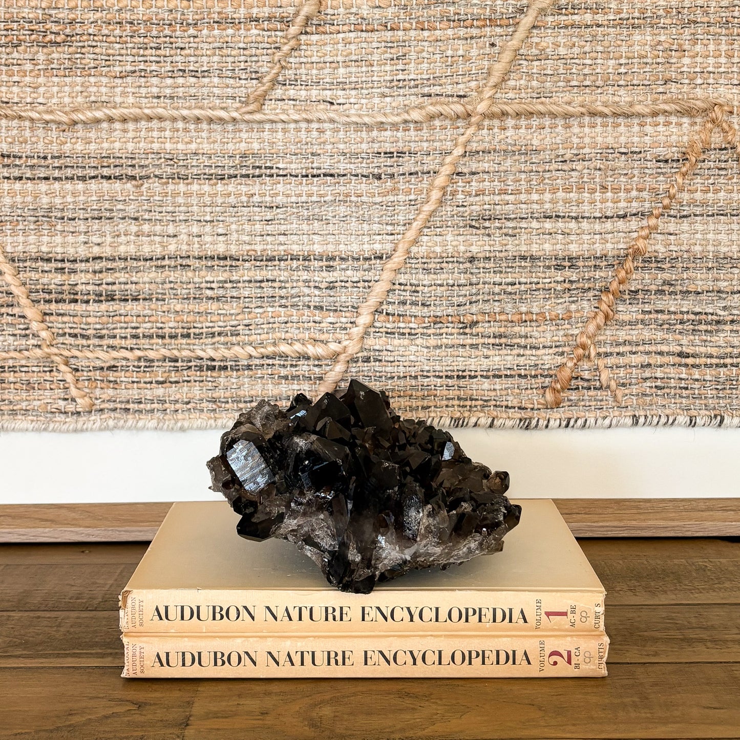 Smoky quartz crystal cluster displayed on vintage books as neutral boho home decor accent
