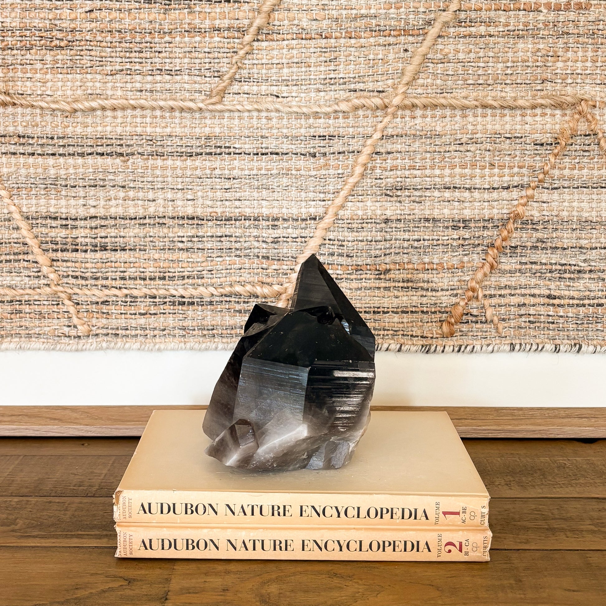 Smoky quartz crystal cluster displayed on vintage books as neutral boho home decor accent