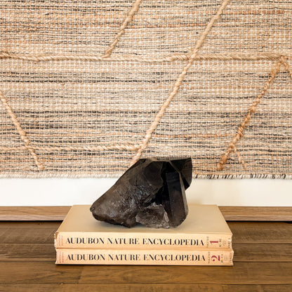 Smoky quartz crystal cluster styled as natural home decor on books