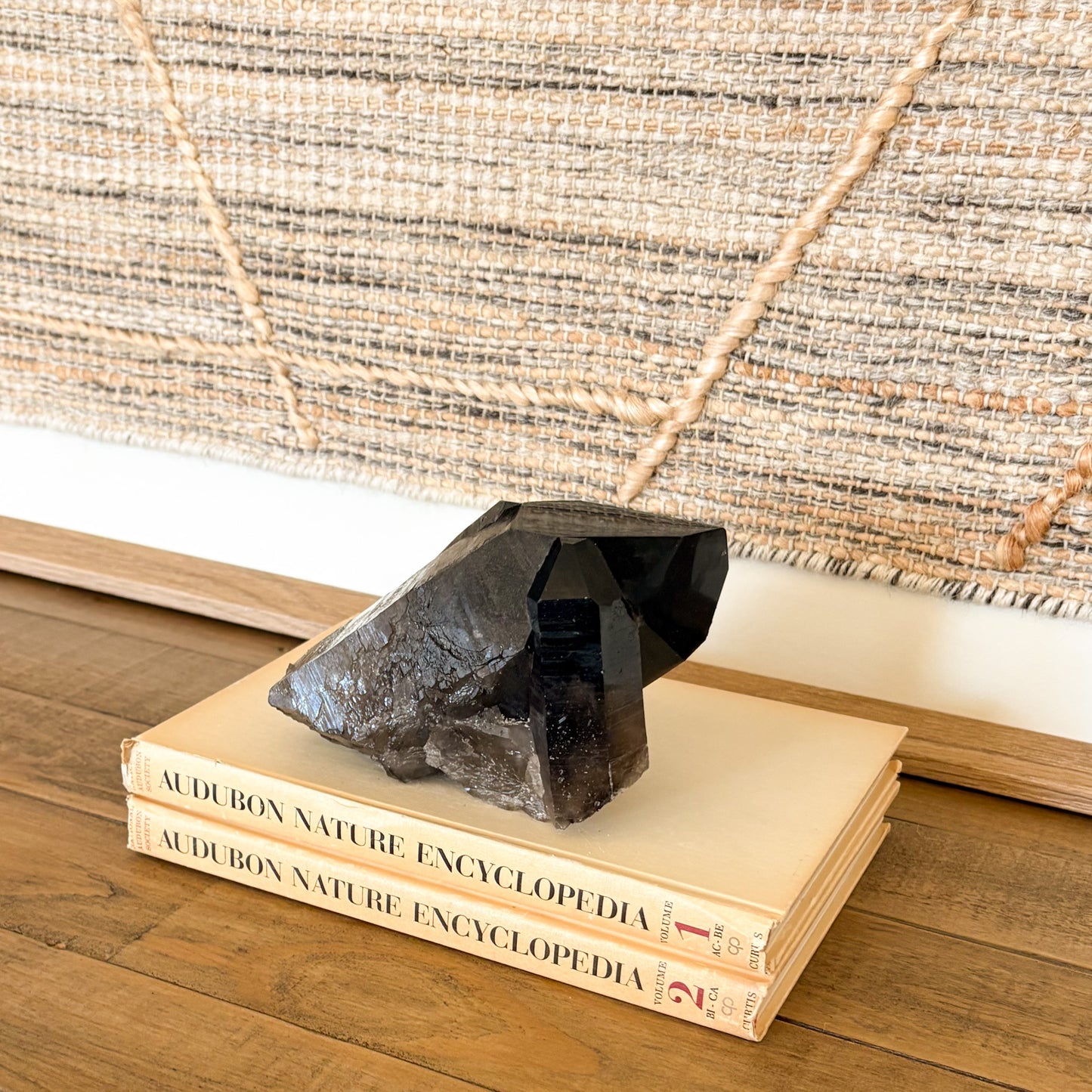 Smoky quartz crystal cluster styled on stacked books for earthy modern home decor