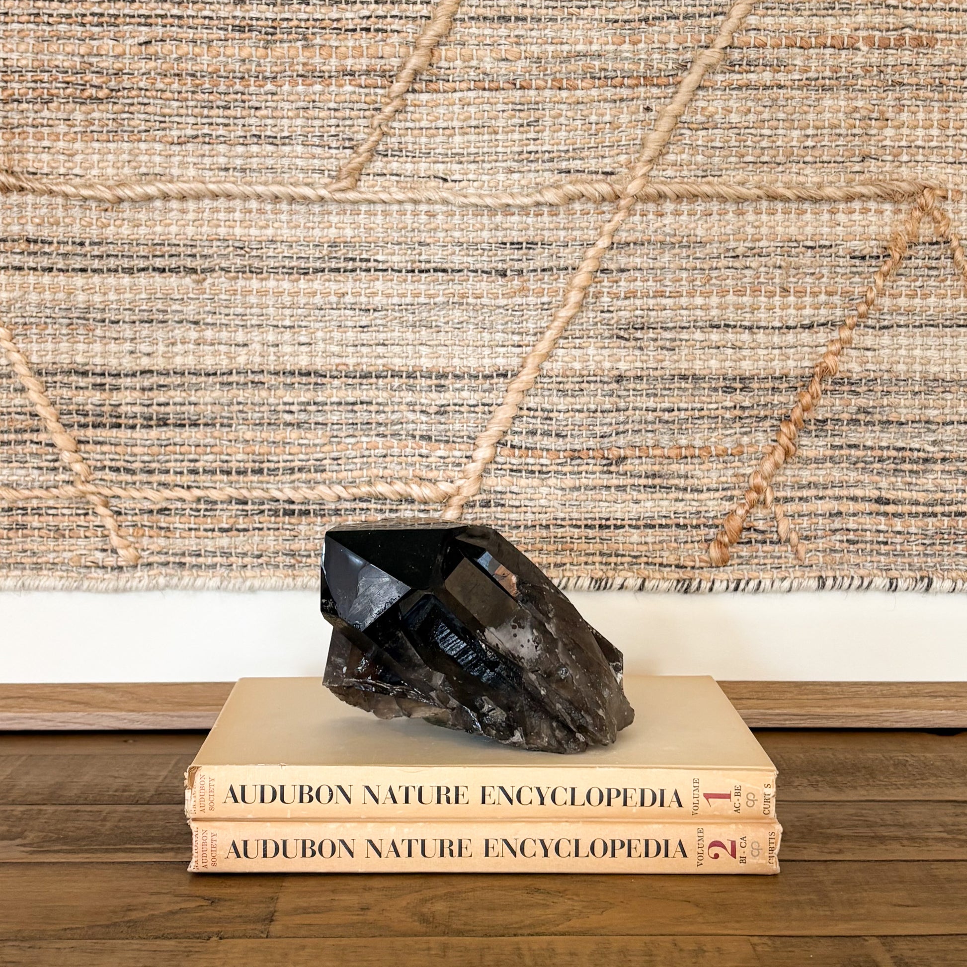 Smoky quartz crystal cluster displayed on vintage books as neutral boho home decor accent