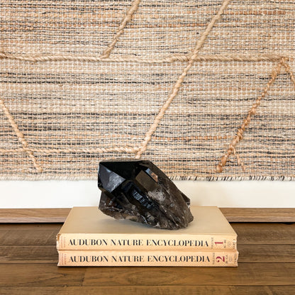 Smoky quartz crystal cluster displayed on vintage books as neutral boho home decor accent