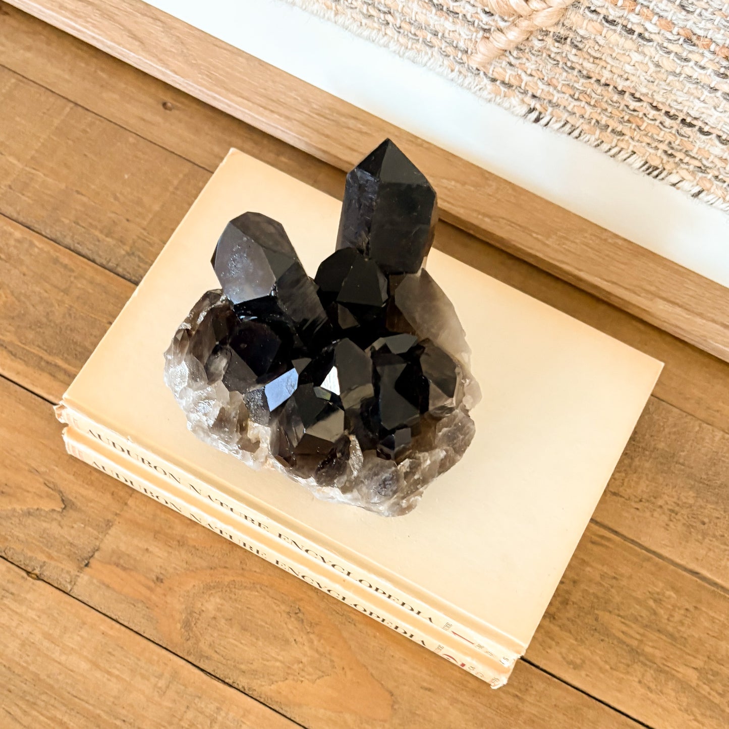 Smoky quartz crystal cluster styled as natural home decor on books