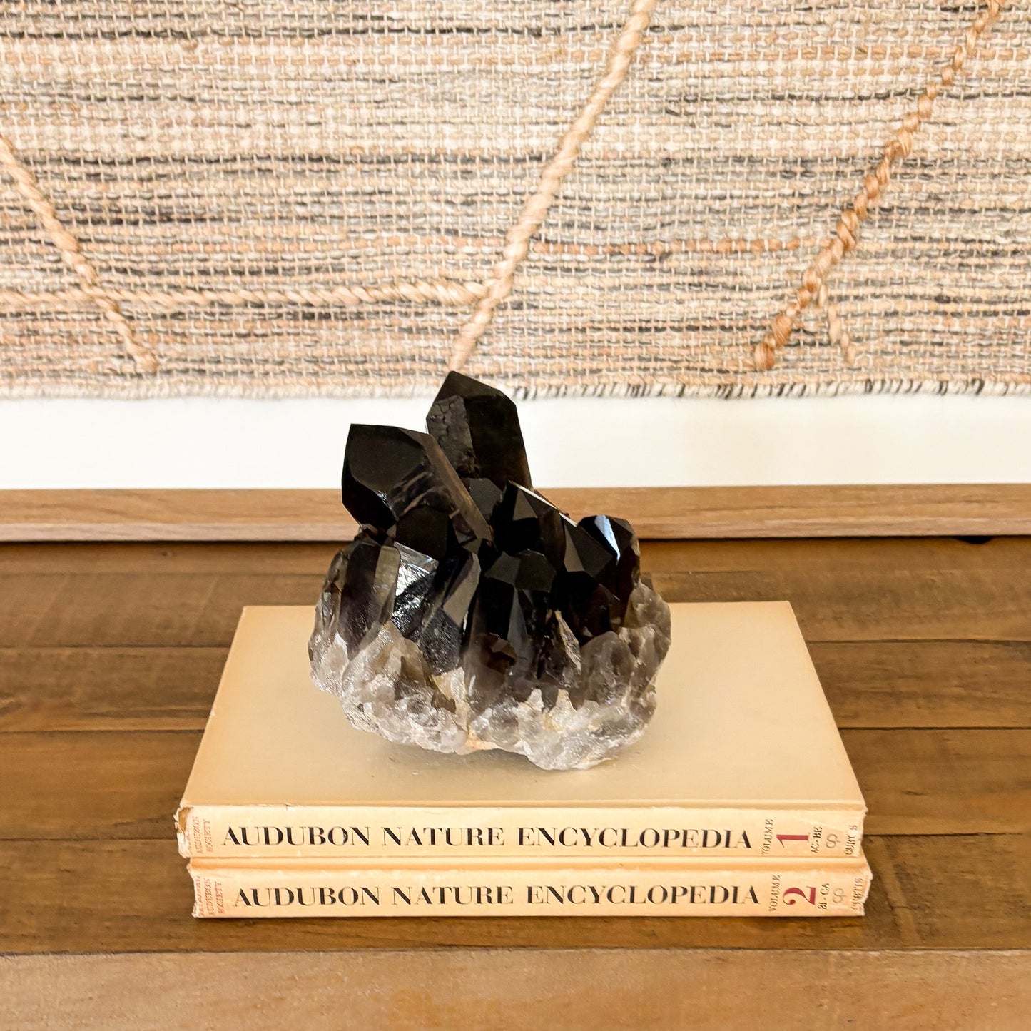 Smoky quartz crystal cluster displayed on vintage books as neutral boho home decor accent