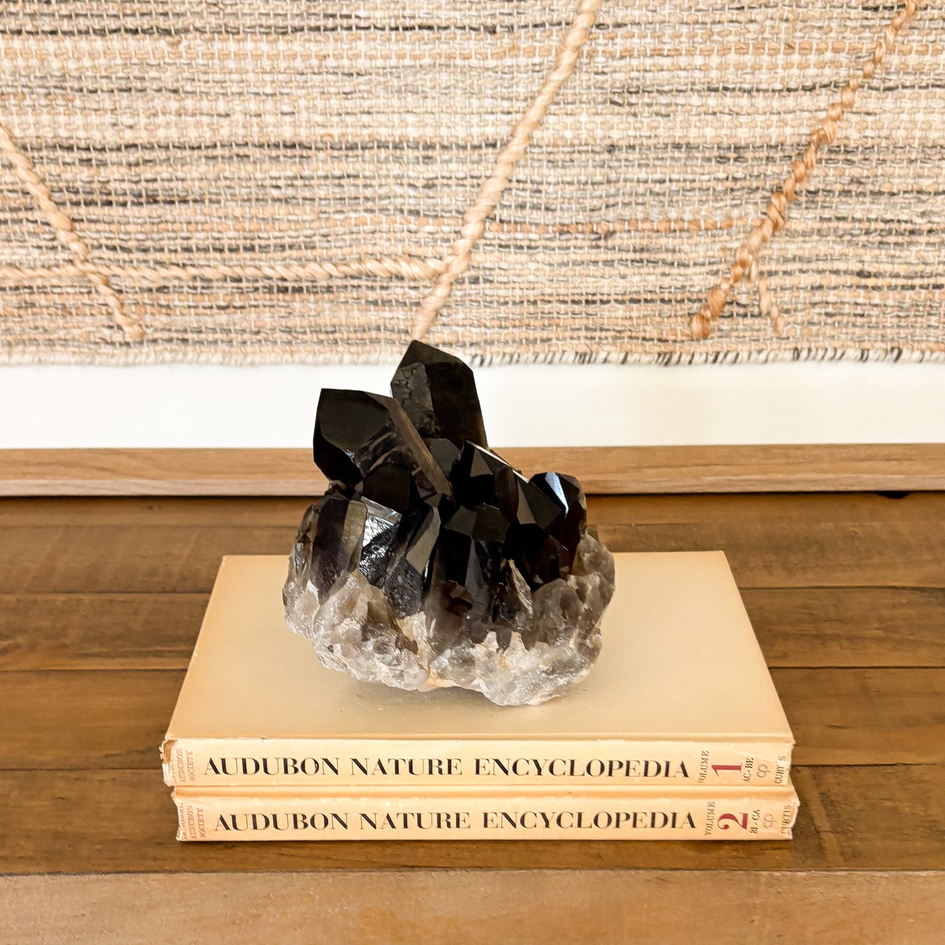 Smoky quartz crystal cluster displayed on vintage books as neutral boho home decor accent