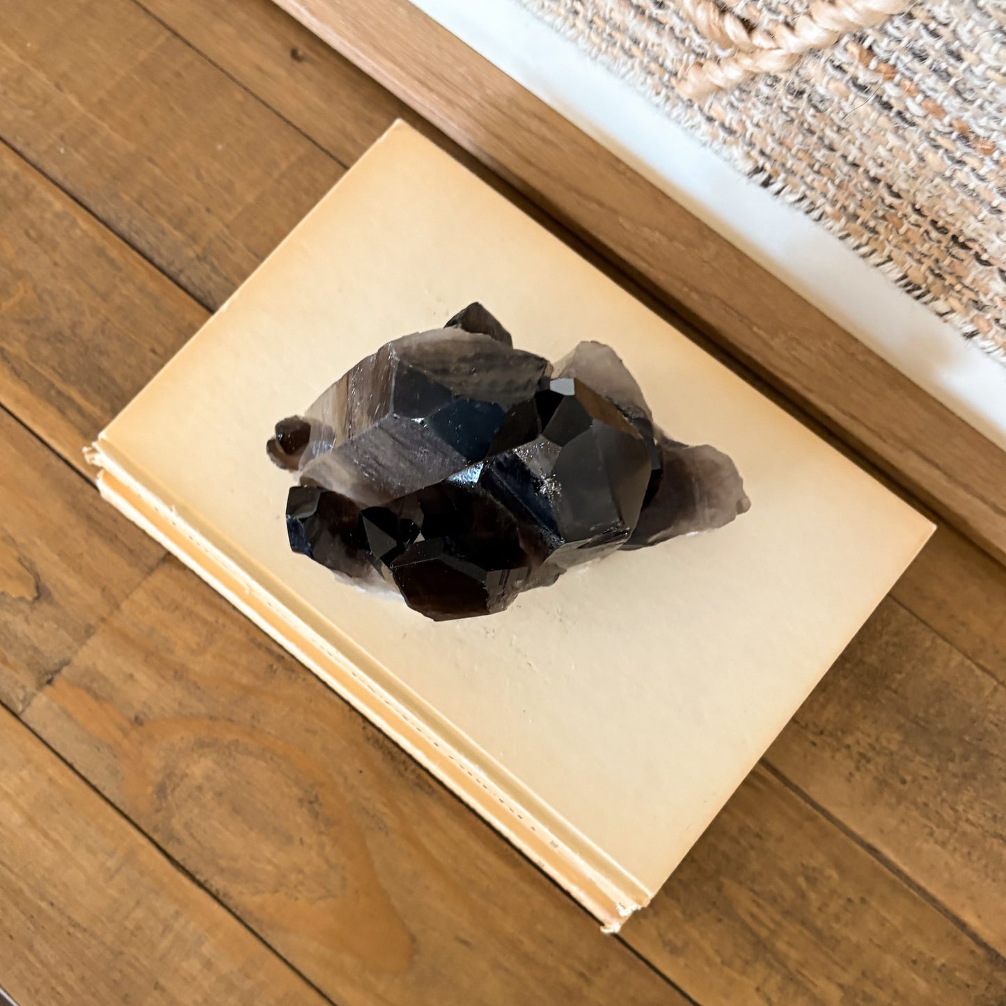 Smoky quartz crystal cluster mineral decor piece styled with vintage books and textile wall art.