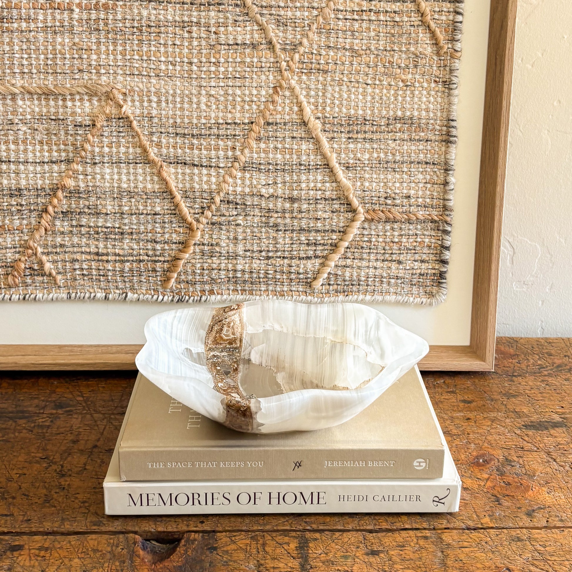 Polished white onyx bowl displayed on stacked design books