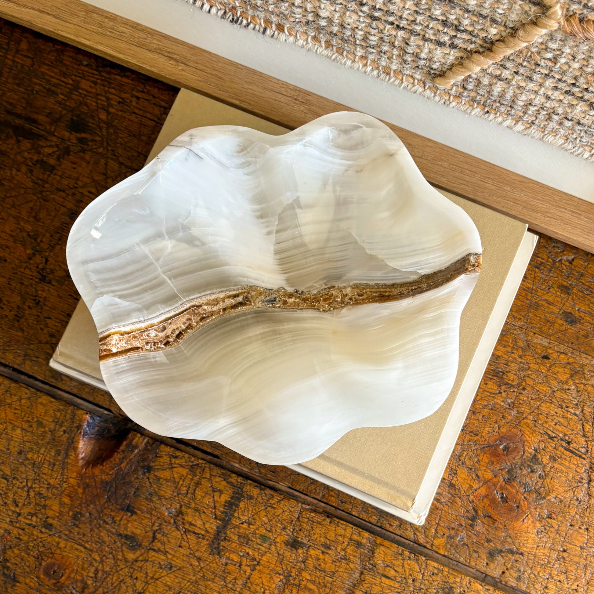 Polished white onyx bowl displayed on stacked design books