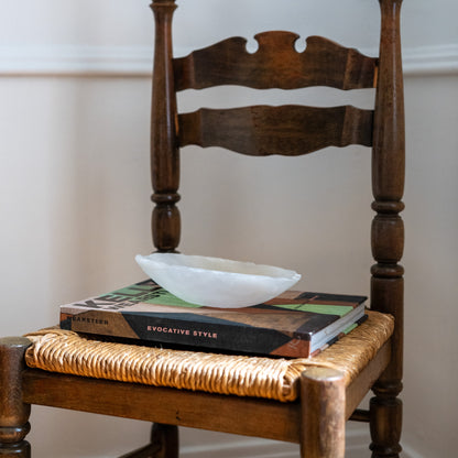 Handcrafted white onyx decorative canoe resting on woven chair with modern rustic styling