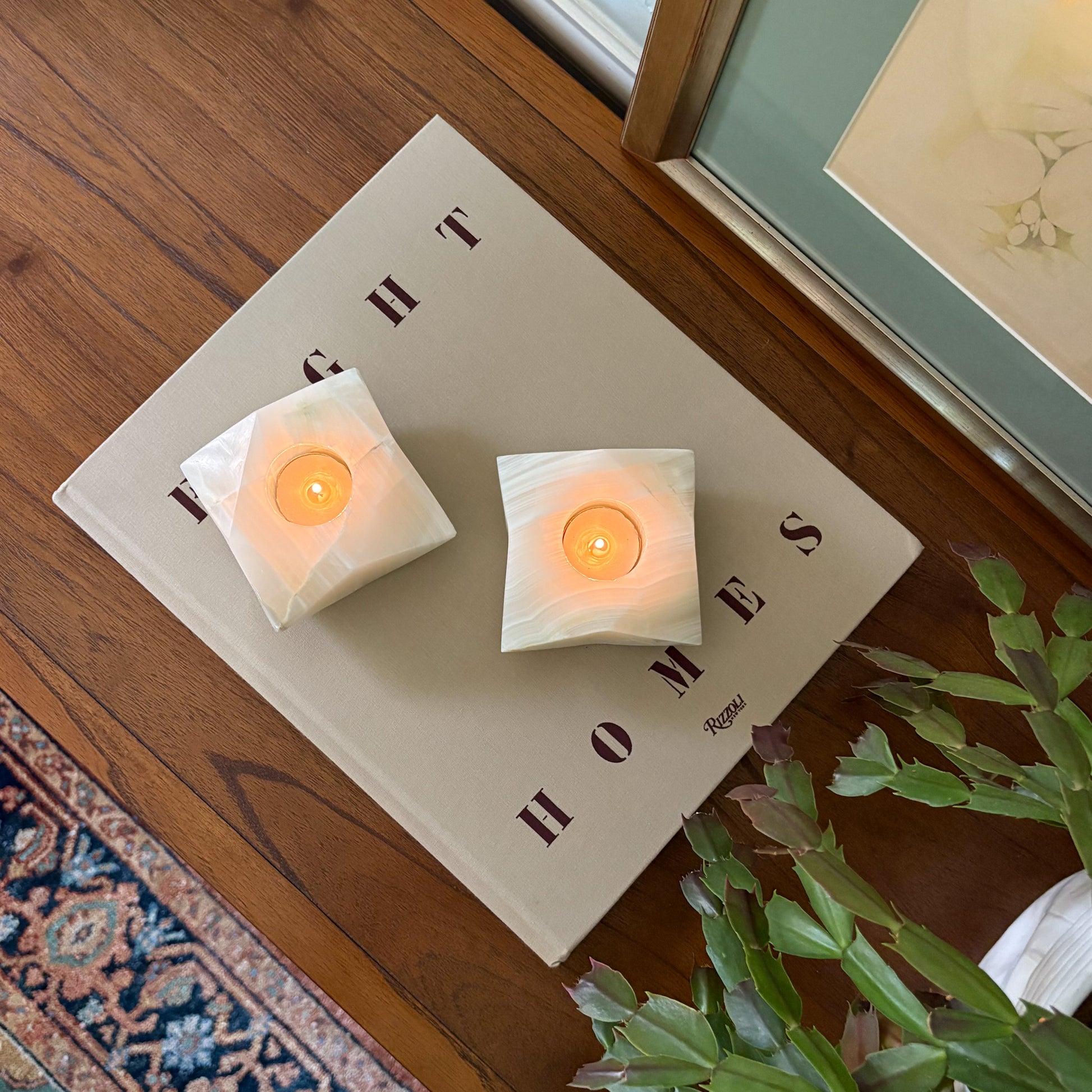 White onyx tealight candle holders with glowing candles on a wooden table