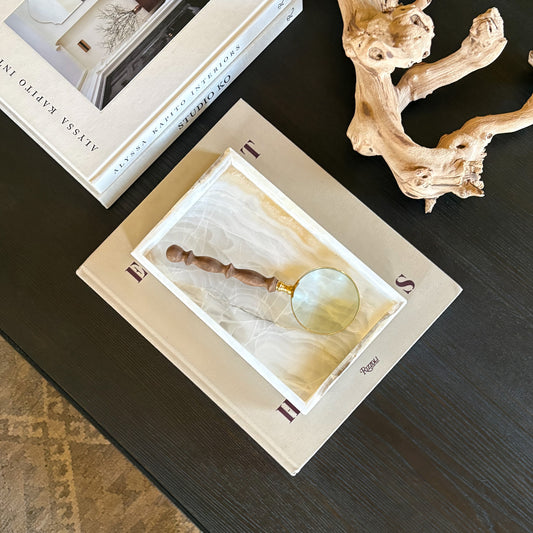 White onyx tray styled on coffee table with books and decorative magnifying glass