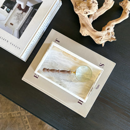 white onyx decorative tray styled on books with magnifying glass and driftwood decor