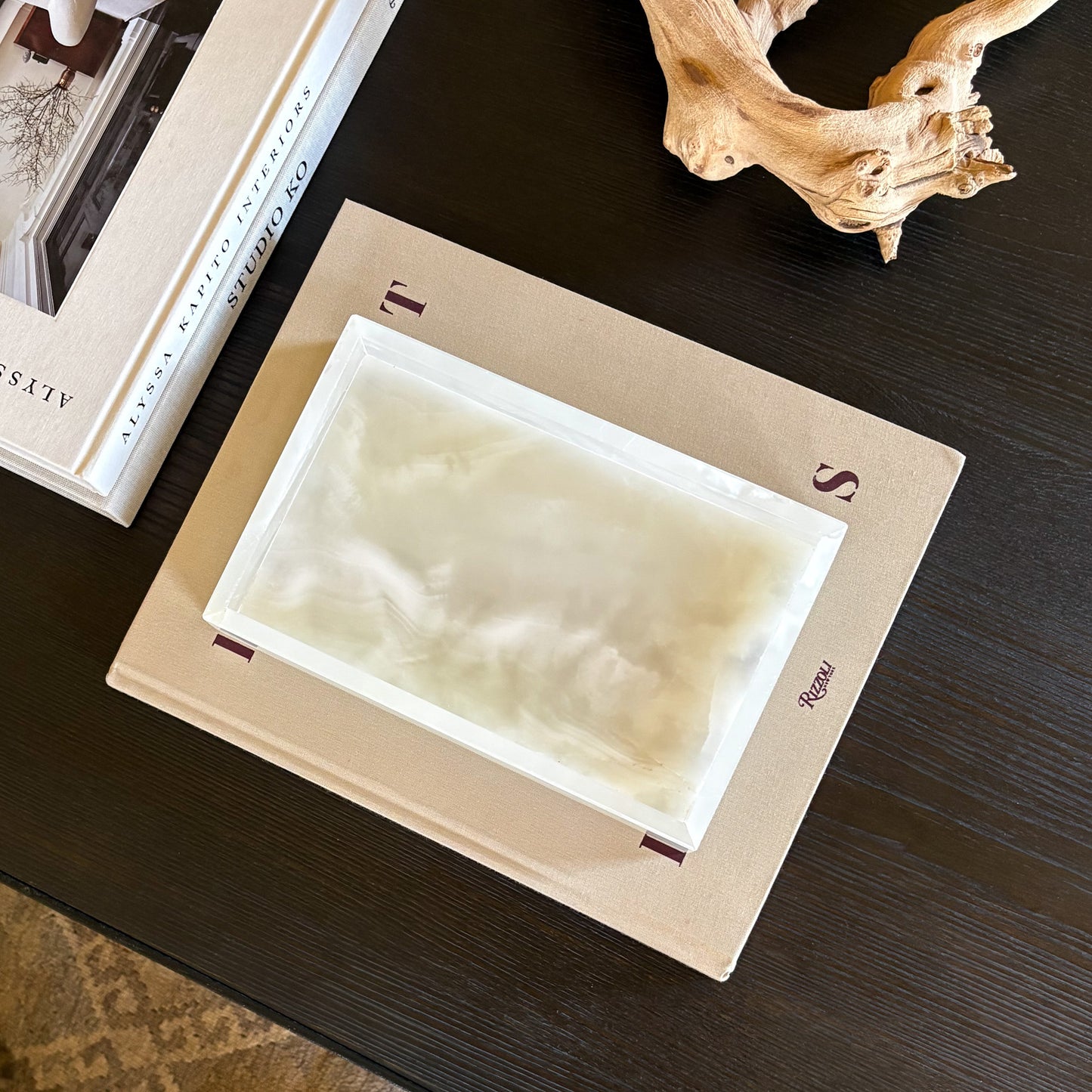 white onyx decorative tray styled on books with magnifying glass and driftwood decor