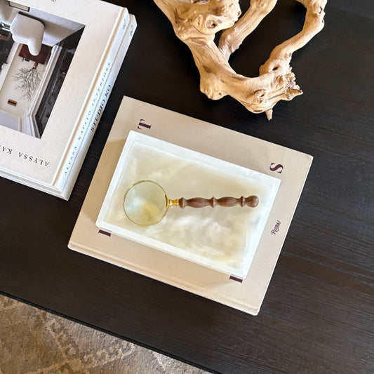 White onyx tray styled on coffee table with books and decorative magnifying glass