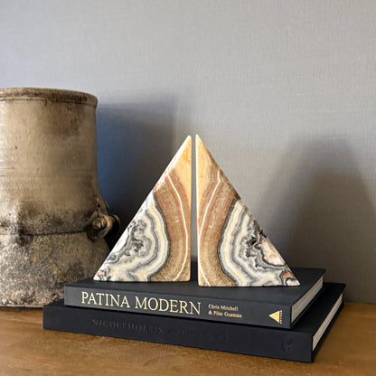 Hand carved zebra calcite bookend pair with natural brown, cream and gray banding displayed on modern coffee table books
