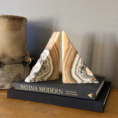 Polished zebra calcite stone bookends pair with earthy striped patterns styled on modern black design books